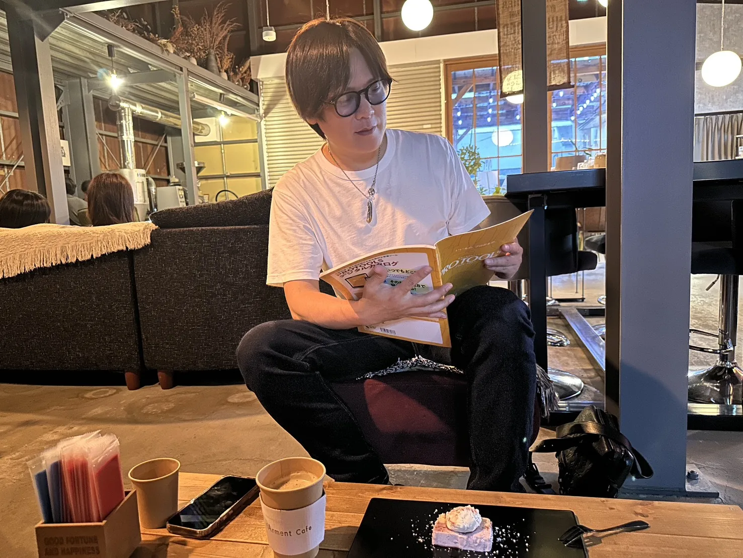 店内で資料を見ながら打ち合わせをする白いTシャツ姿の男性